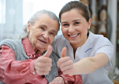 senior woman and caregiver doing thumbs up